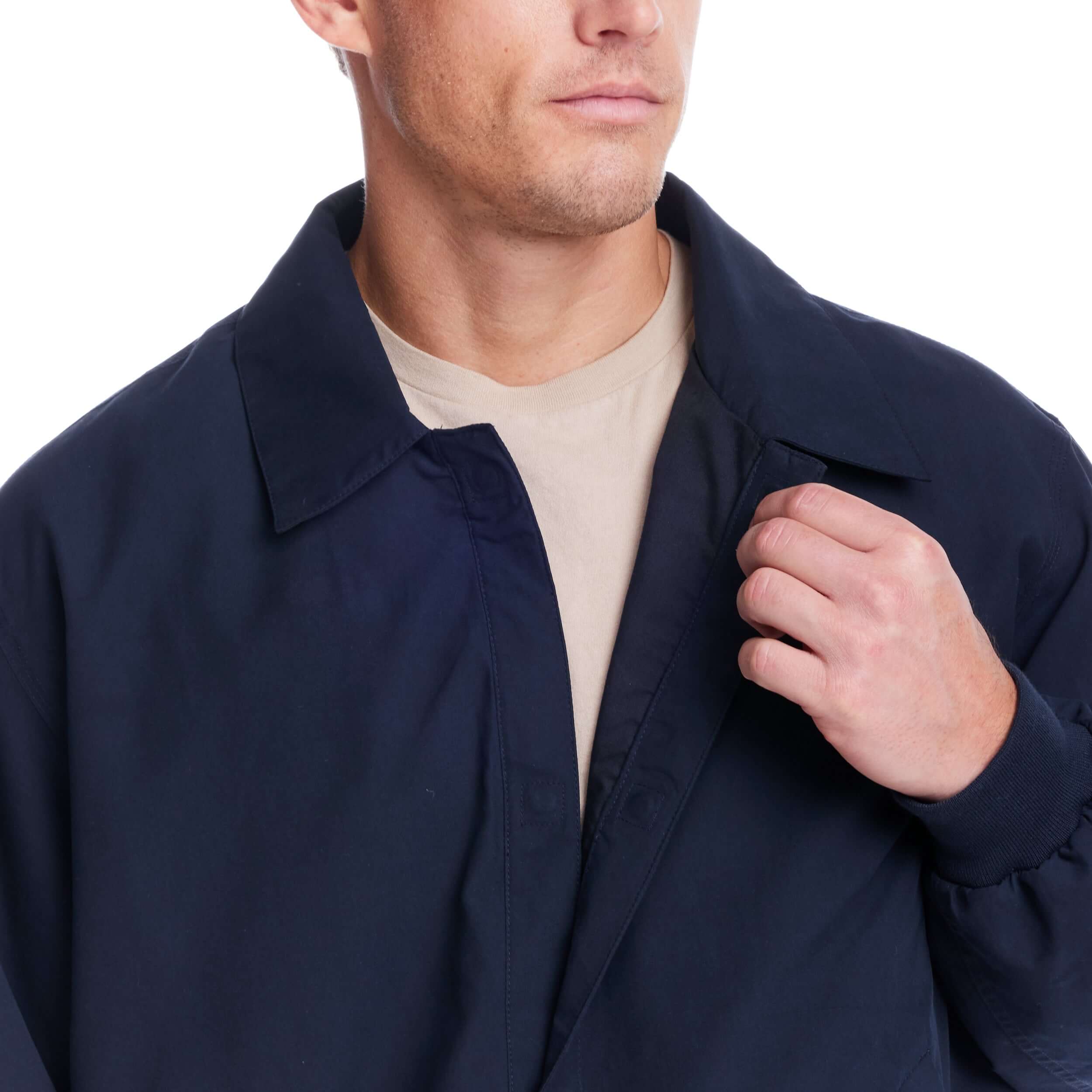 Close-up of a man wearing a weatherproof navy golf jacket with magnetic closures for easy wear.