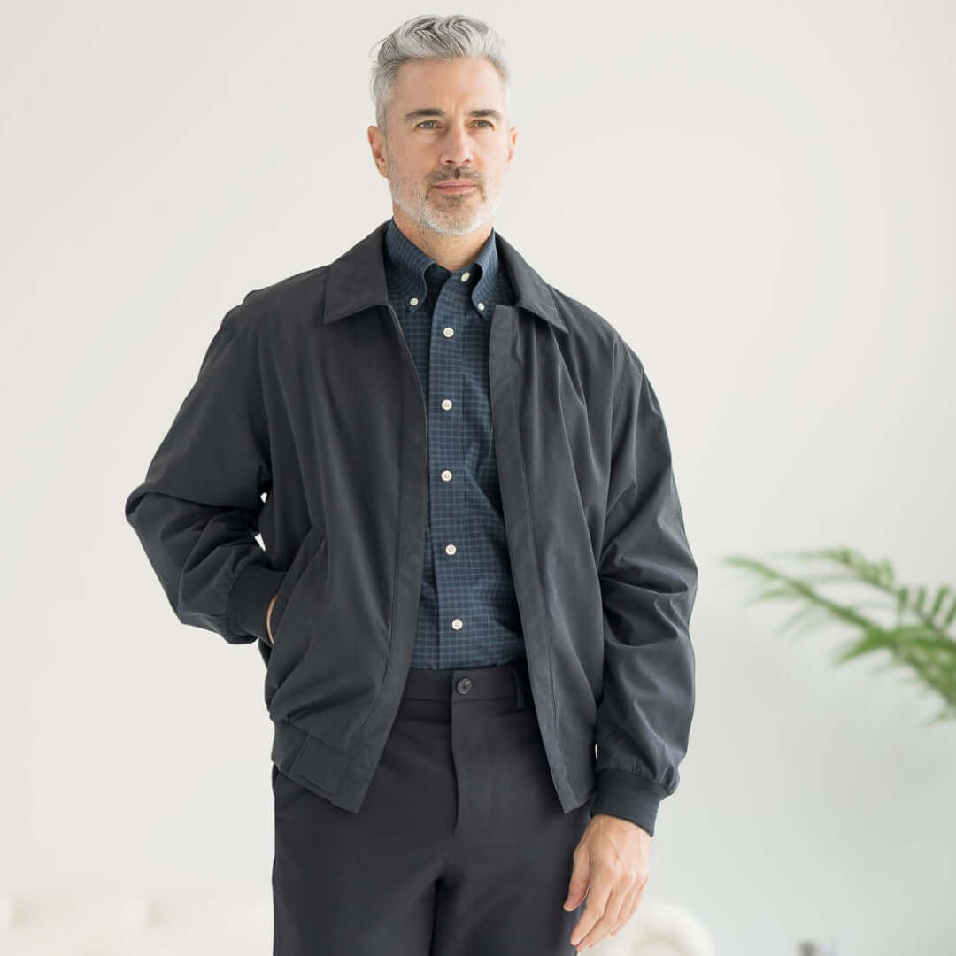 Man wearing a black MagnaReady® X Weatherproof Golf Jacket, showcasing adaptive design and modern style.