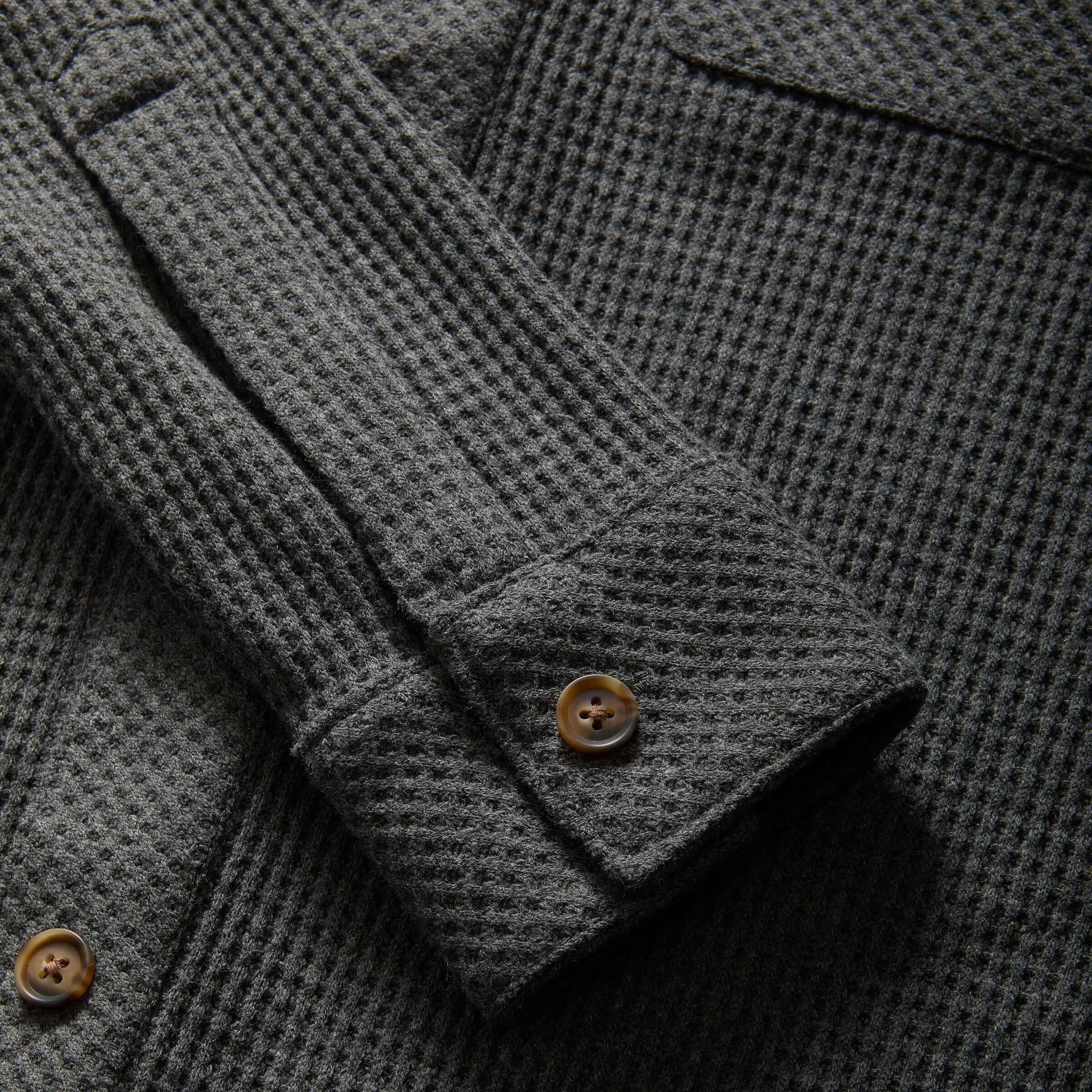 Close-up of a charcoal waffle weave shirt sleeve featuring button detail and dual oversized pockets.