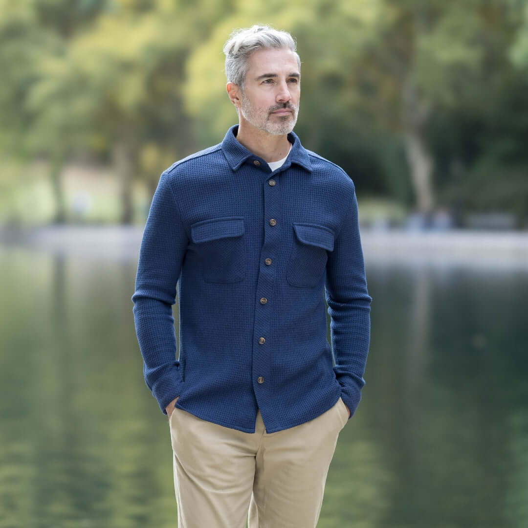 Man in a navy Magnetic Front WaffleWeave Casual Shirt with dual pockets, standing by a serene outdoor lake.