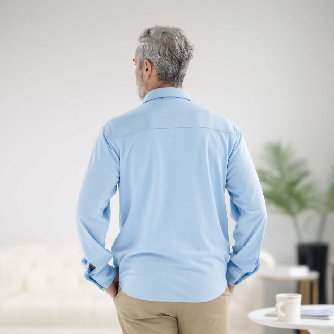 Back view of a man wearing a Carolina Blue MagnaReady magnetic long sleeve shirt in a modern home setting.