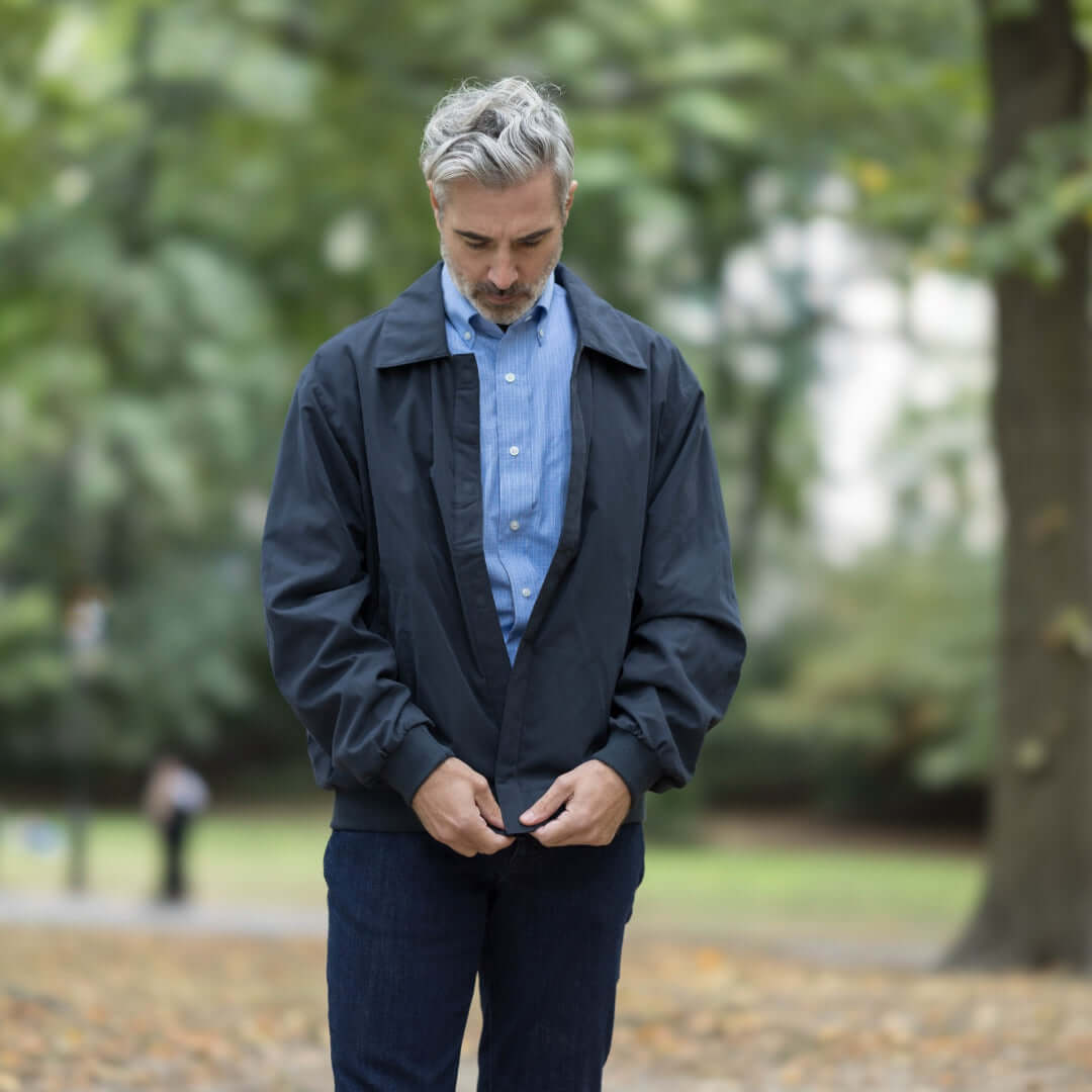 Man wearing a MagnaReady® X Weatherproof Navy Golf Jacket in a park, showcasing its adaptive design and style.