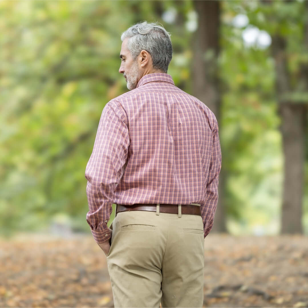 Man in a plaid shirt standing outdoors, showcasing the back view in a natural setting.