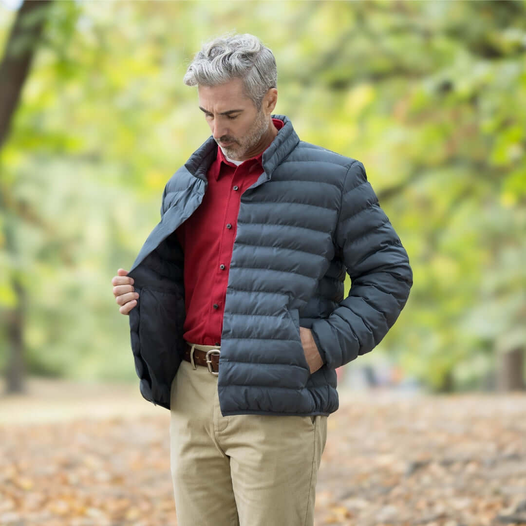 Man wearing a dark puffer jacket over a red shirt outdoors in a fall setting.