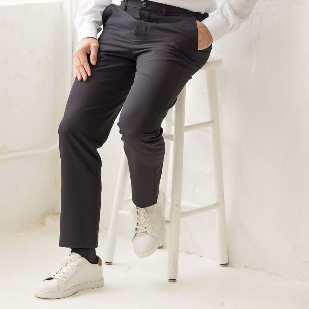Modern adaptive dress pants in black by Nautica x MagnaReady, displayed on a person sitting on a stool.