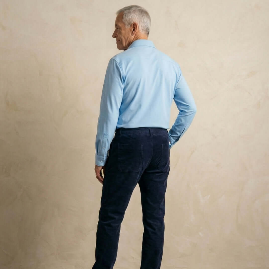Man wearing Navy Fine Wale Adaptive Corduroy Magnetic Fly Front Pant and light blue shirt from the back.