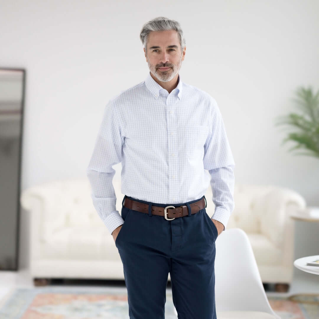 Man wearing a navy grid long sleeve shirt with button-down collar, standing confidently in a modern room.