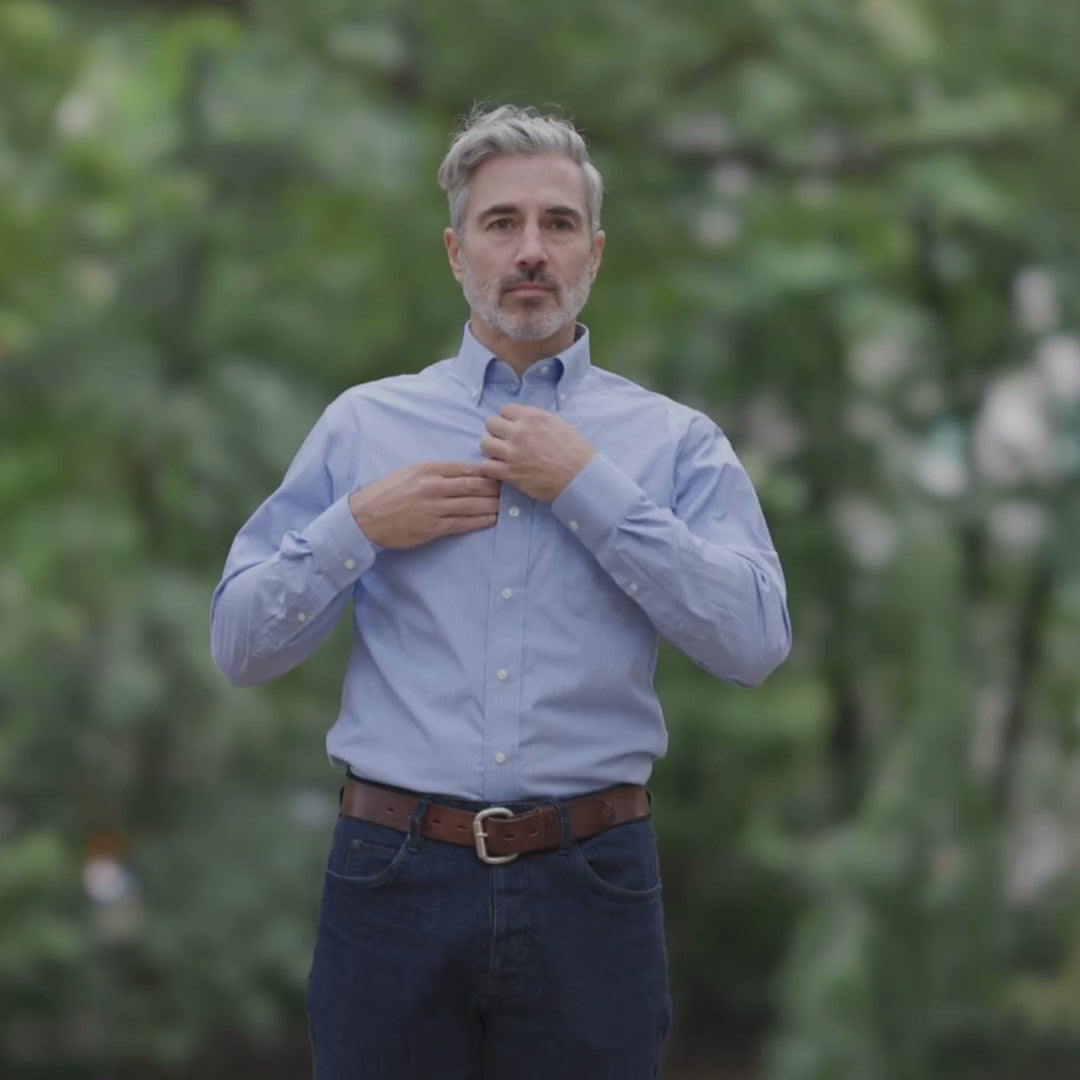 Man wearing a blue long sleeve button-down collar shirt with magnetic closures outdoors.