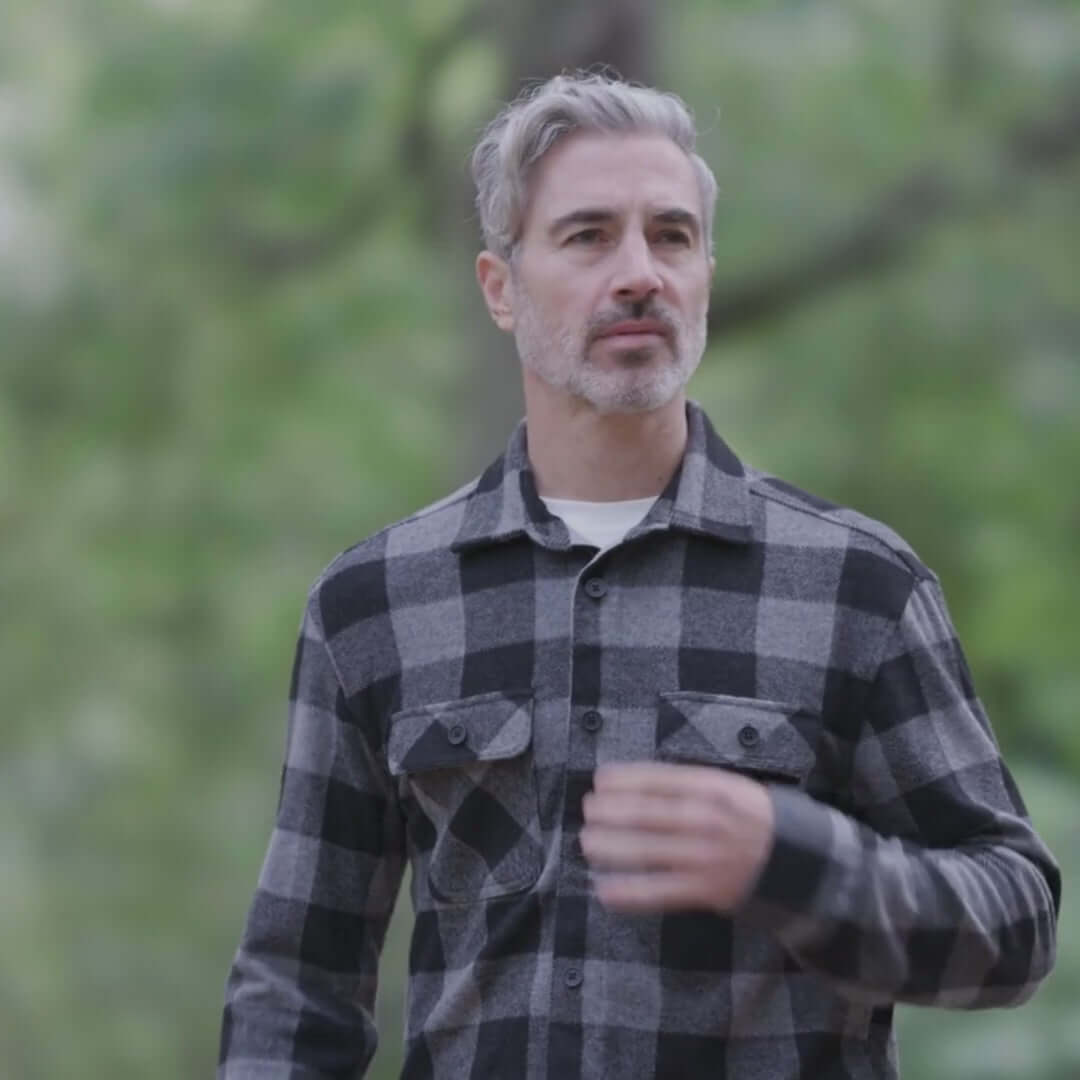 Man wearing a black buffalo check flannel shirt outdoors, showcasing a versatile layering piece.