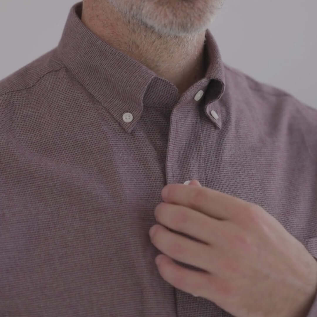 Man adjusting the collar of a red and grey long sleeve shirt with magnetic closures, designed for ease of dressing.