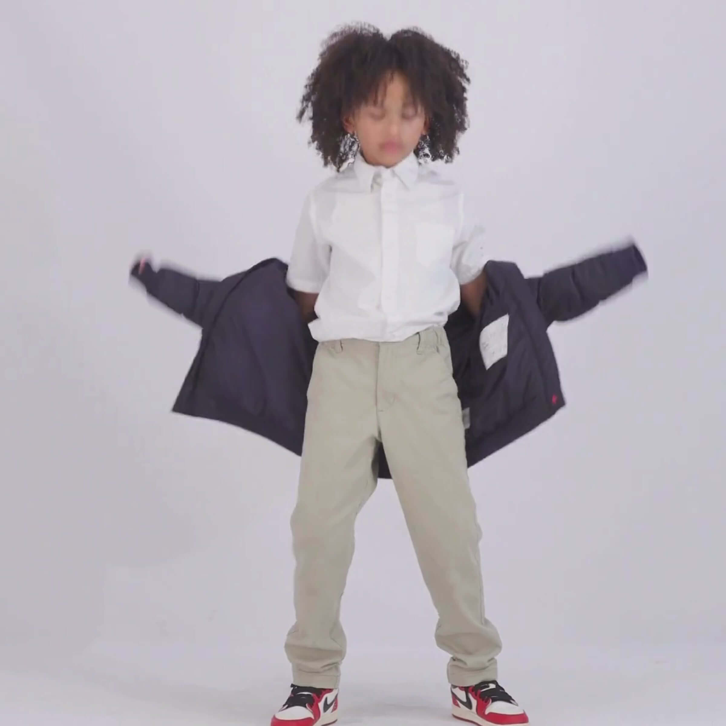 Child putting on a pink MagnaMini kids magnetic puffer coat, showcasing easy dressing and independence.
