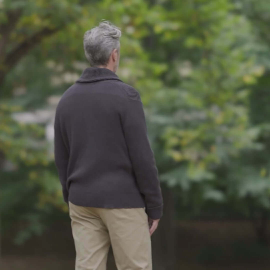 Man wearing a charcoal adaptive ribbed shawl collar cardigan in a natural outdoor setting.