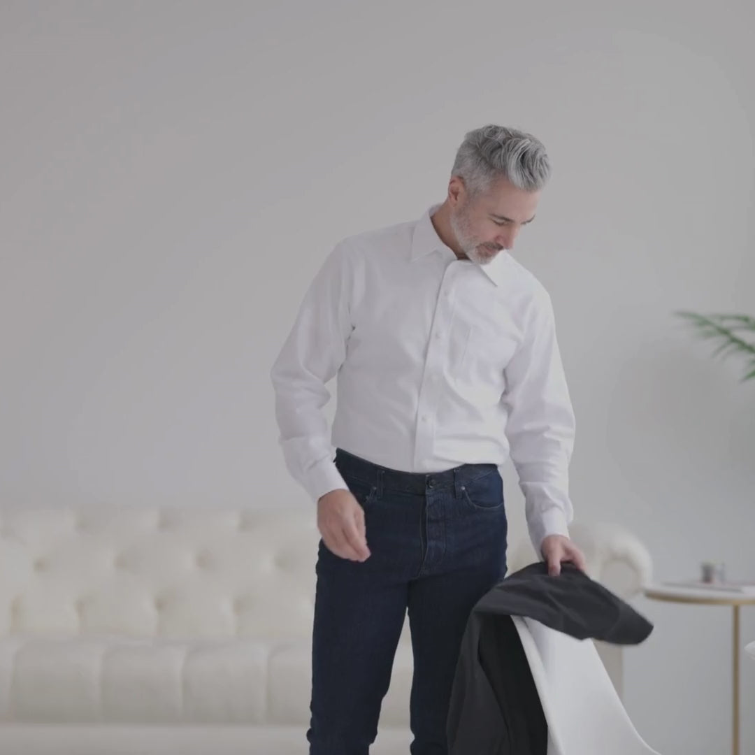 Man in white shirt preparing to wear a MagnaReady golf jacket, showcasing adaptive and stylish design.