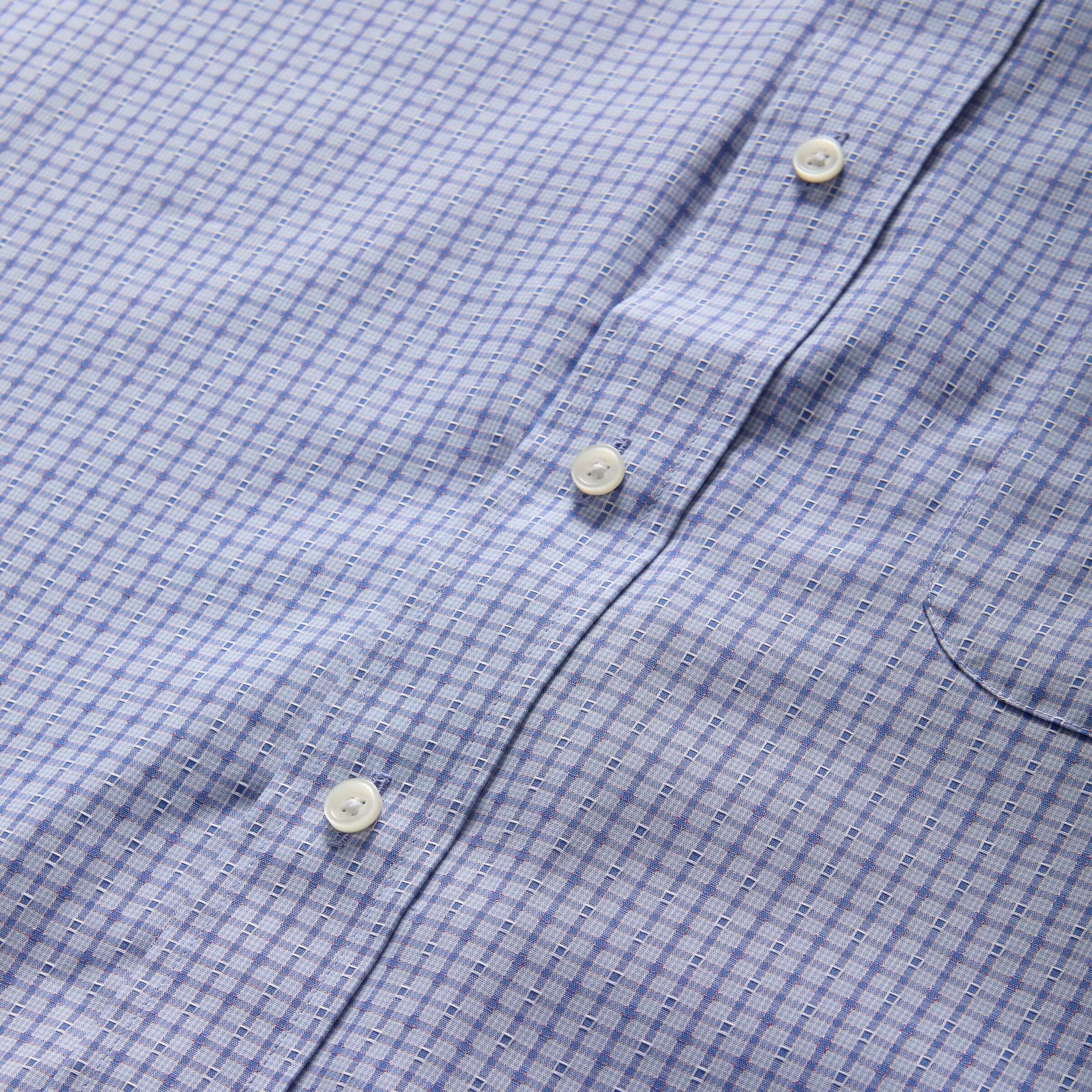 Close-up of a short sleeve blue and red check cotton shirt featuring buttons and a pocket detail.