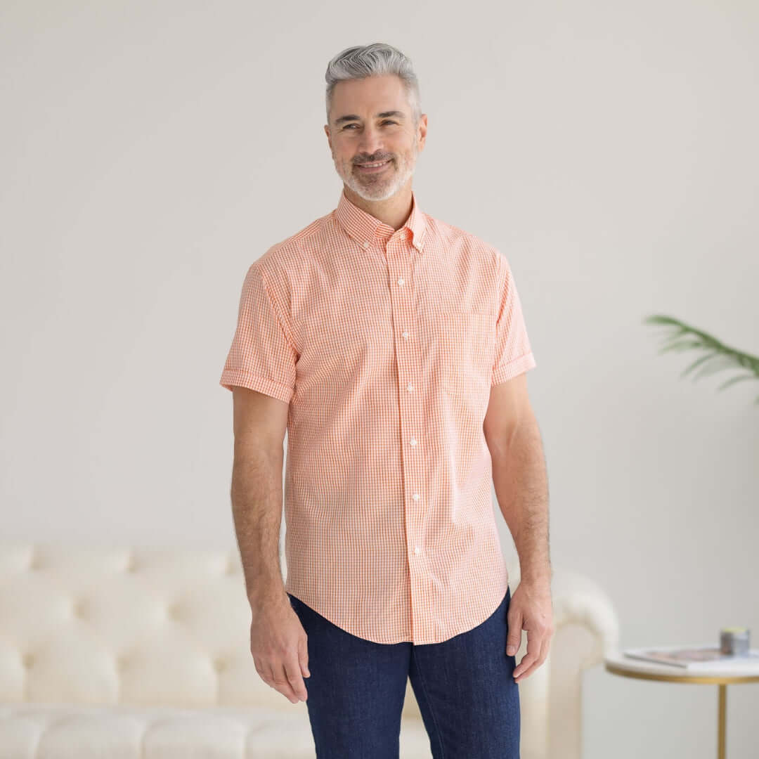 Man wearing a short sleeve orange and white gingham cotton shirt, showcasing the adaptive MagnaReady design.