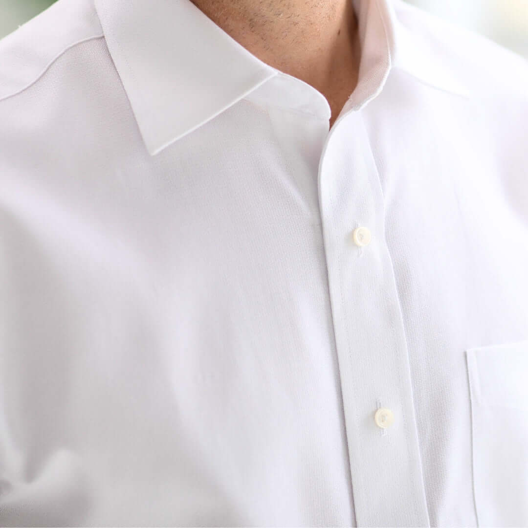 Close-up of a crisp white short sleeve shirt with a spread collar and button details.