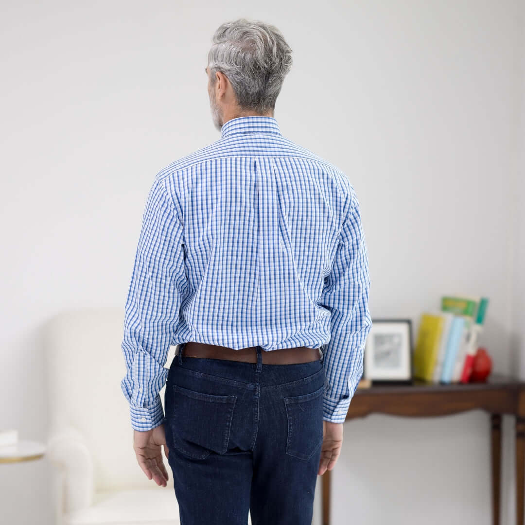 Back view of a man wearing a white and blue plaid long sleeve MagnaReady adaptive shirt.