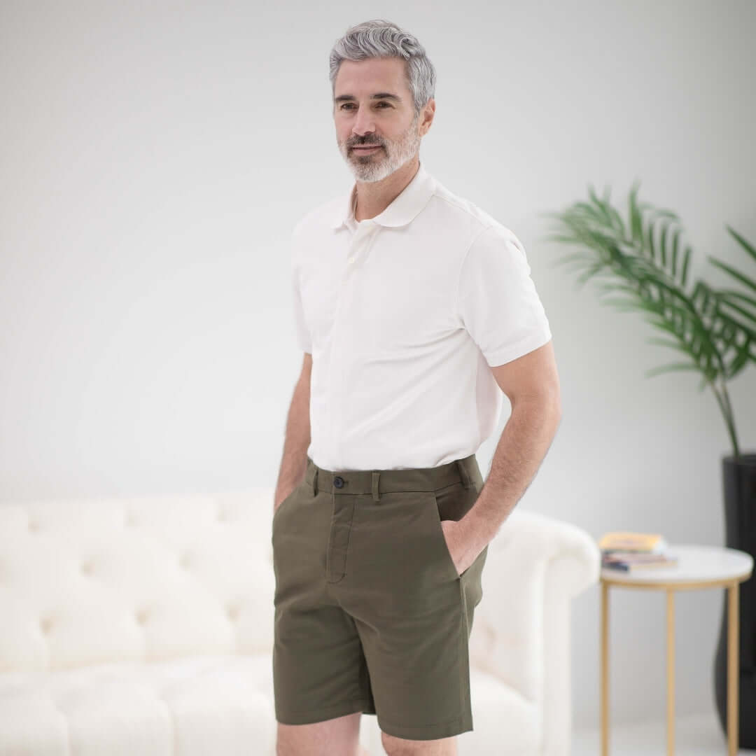 Man in white pique knit polo shirt with magnetic closures, paired with olive green shorts, showcasing adaptive style.