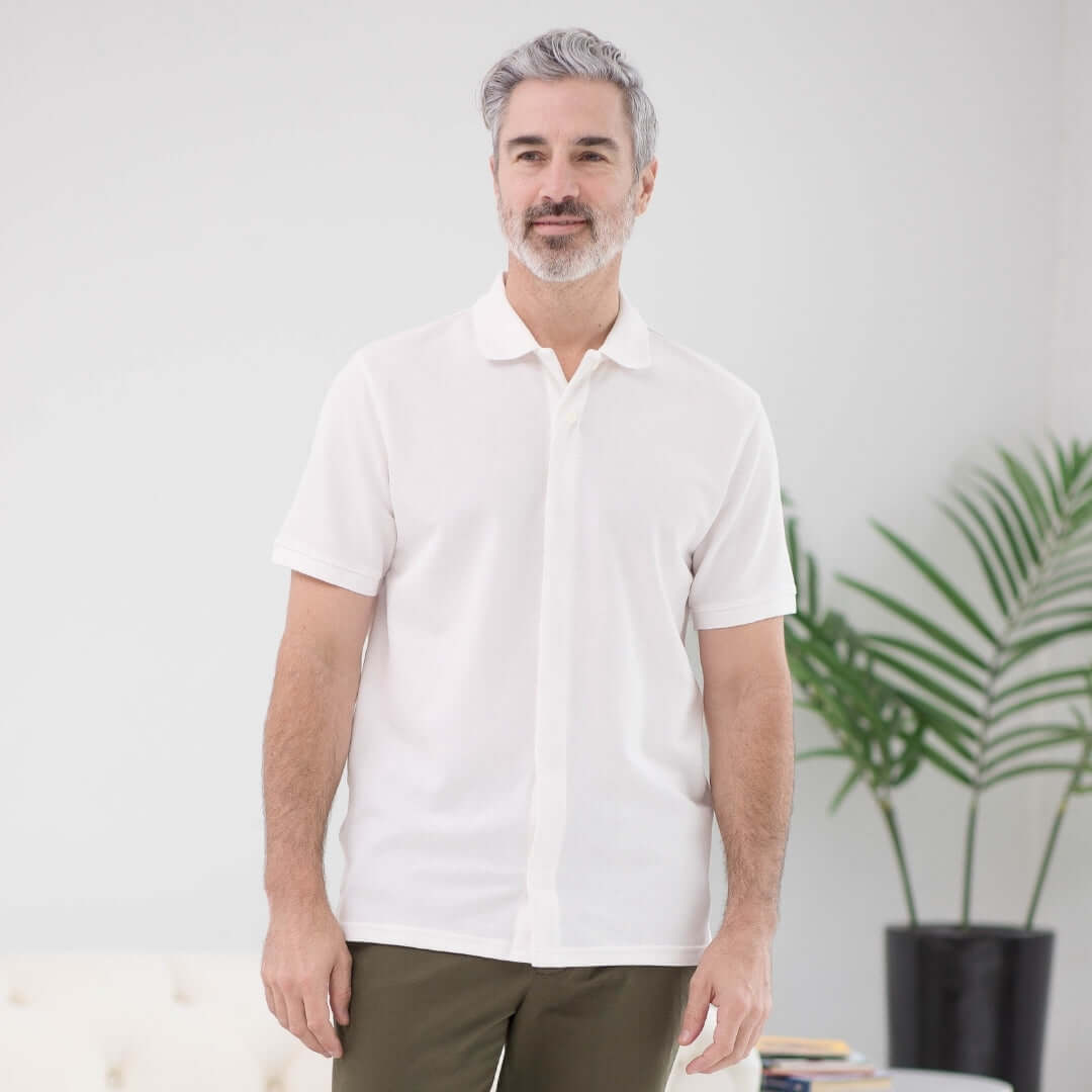 Man wearing a white pique knit short sleeve polo with magnetic closures, ideal for easy dressing and comfort.