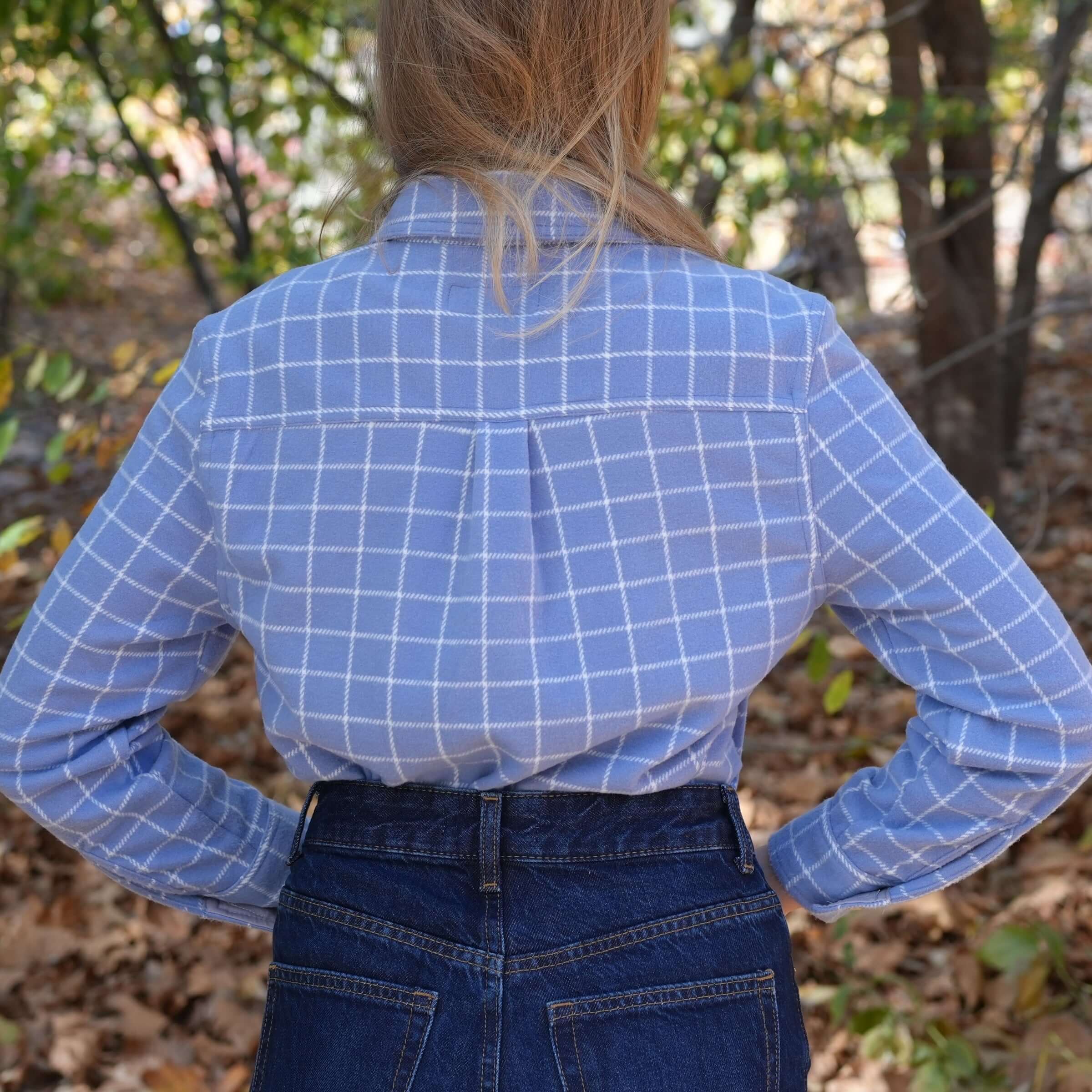 Back view of women's blue and white plaid flannel shirt, showcasing stylish curved hem design.