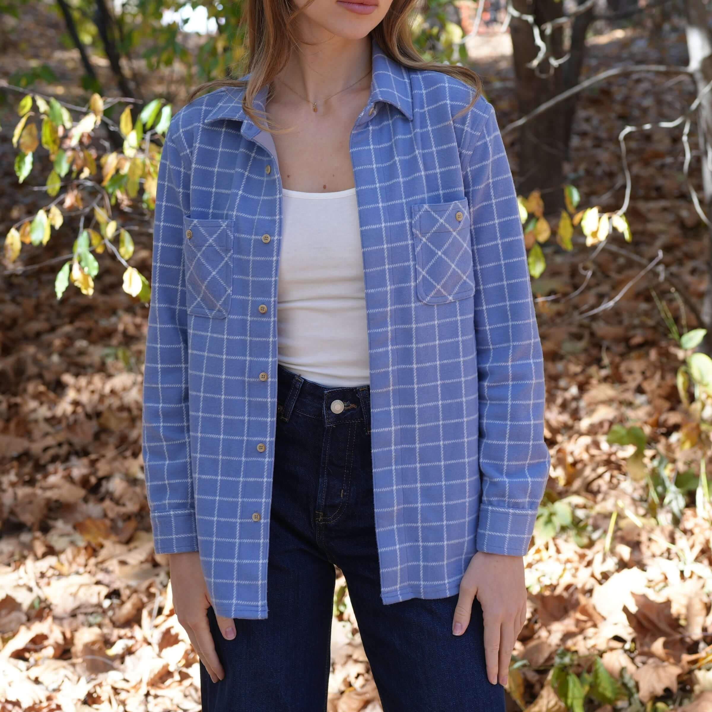 Woman wearing a blue and white window flannel shirt in autumn leaves, showcasing casual style and comfort.