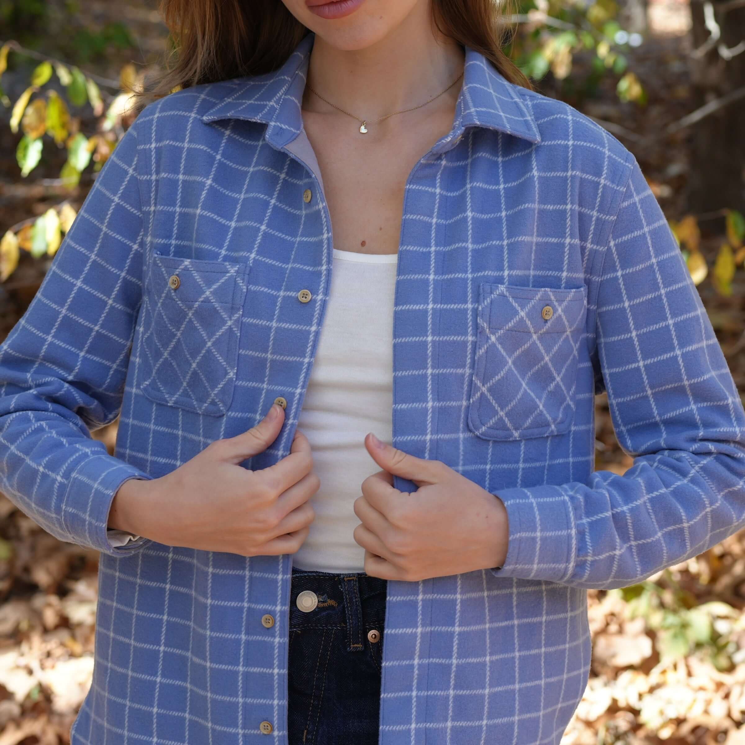 Women's blue and white checkered flannel shirt with front pockets, styled for comfort and elegance in a fall setting.