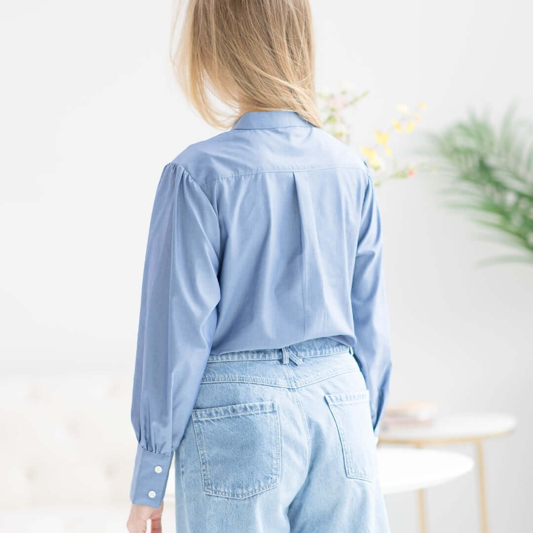 Back view of a woman wearing a Women's Adaptive Magnetic Chambray Blouse with puffed sleeves, perfect for stylish occasions.