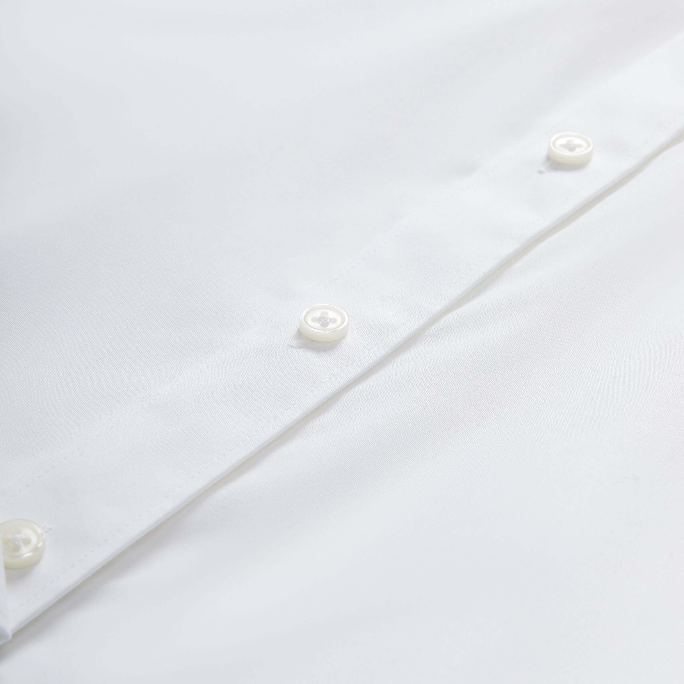Close-up of the button detail on a women's classic white adaptive blouse featuring smooth, soft fabric.