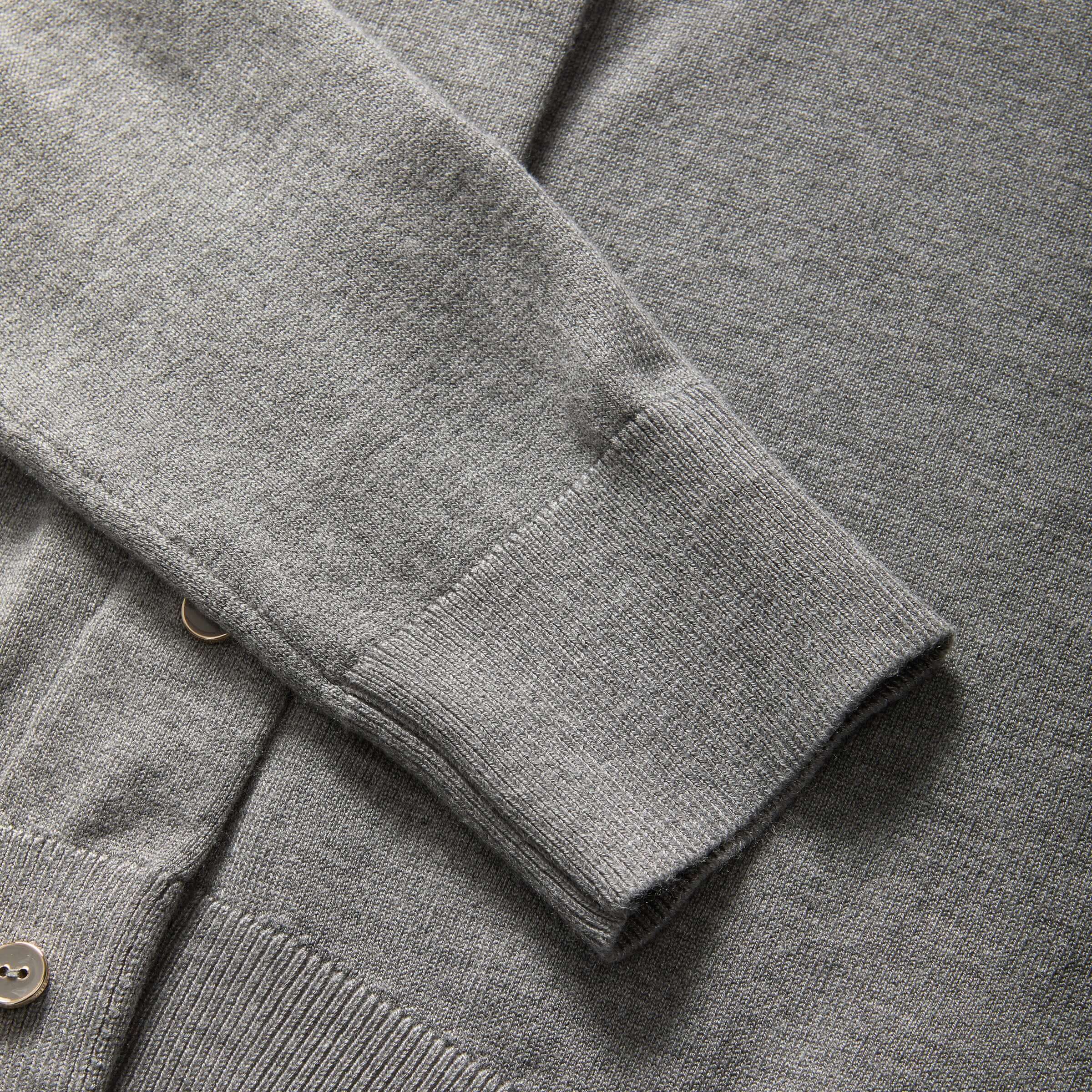Close-up of the sleeve of a women's adaptive grey cardigan sweater, showcasing soft knit fabric and buttons.