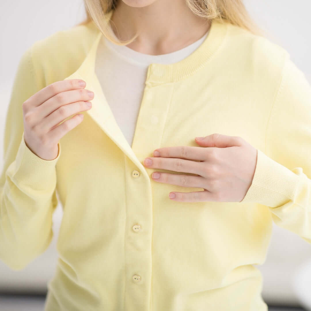 Woman wearing a yellow adaptive cardigan sweater with magnetic closures, demonstrating ease of dressing.