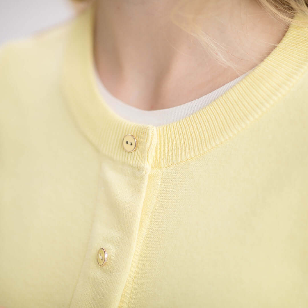 Close-up of yellow women's adaptive cardigan sweater showcasing its buttons and knit texture.