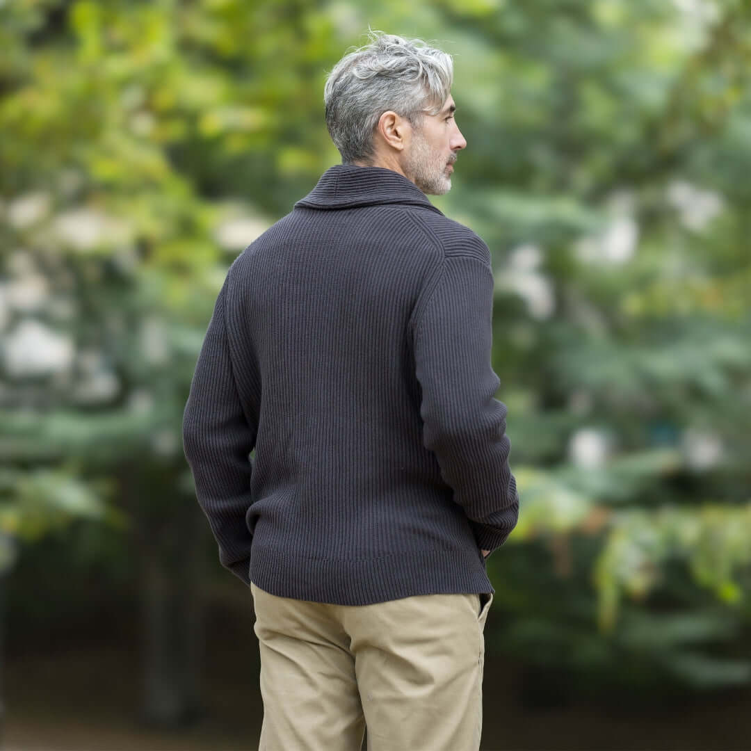 Back view of a man wearing a charcoal ribbed cardigan in an outdoor setting.