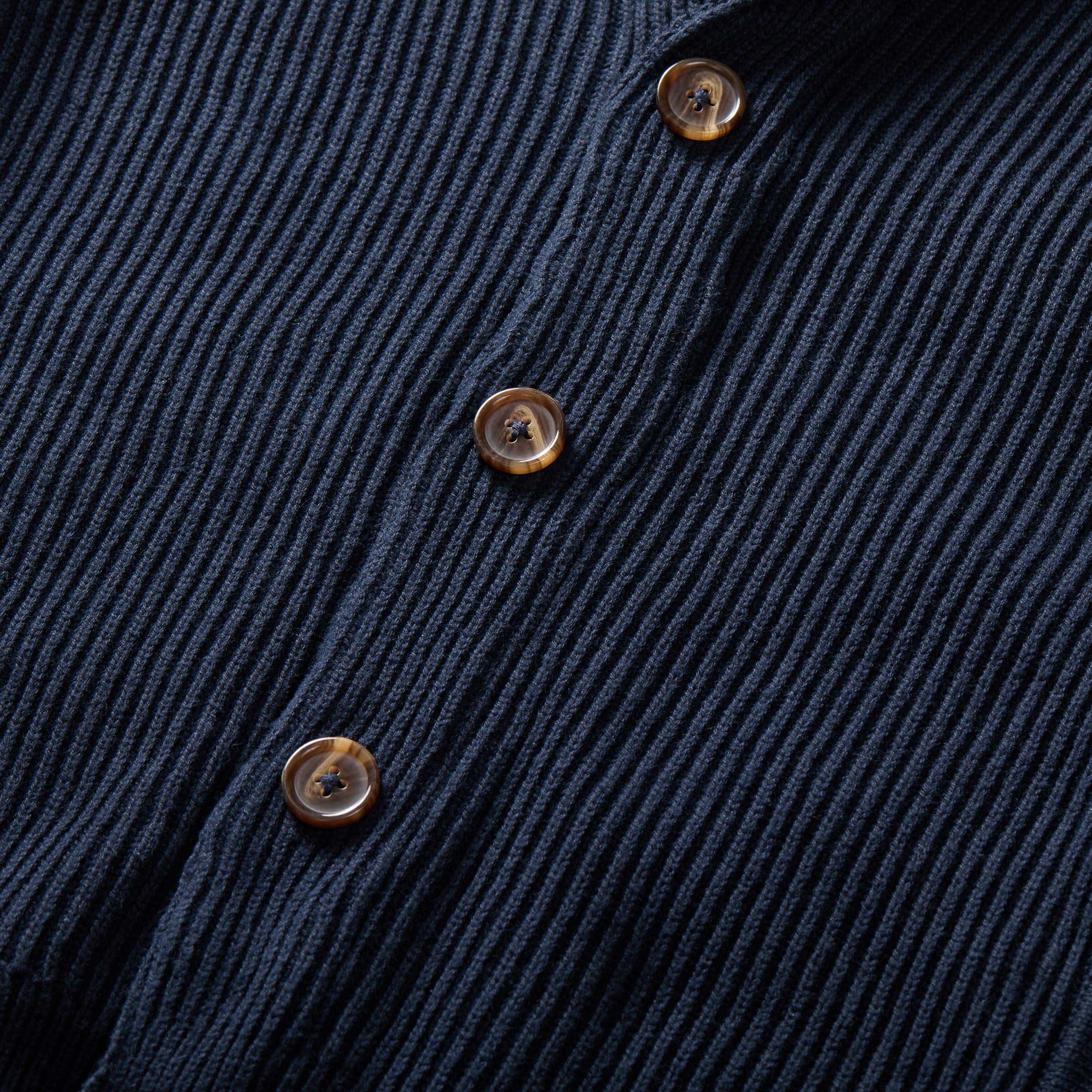 Close-up of navy ribbed cardigan showing magnetic button front and textured fabric.