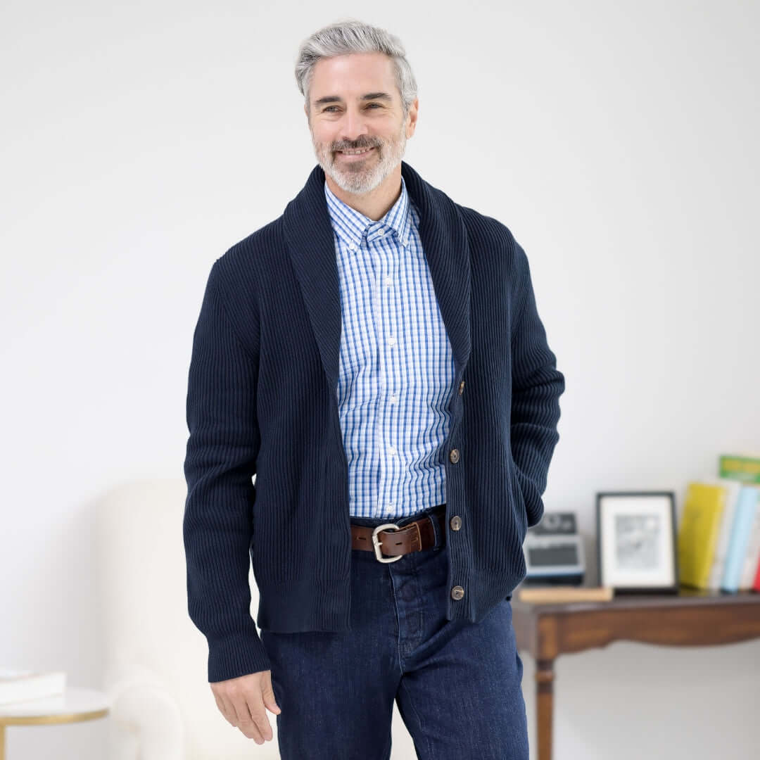 Man wearing a navy ribbed cotton shawl collar cardigan with magnetic buttons and pockets, styled with a blue checkered shirt.