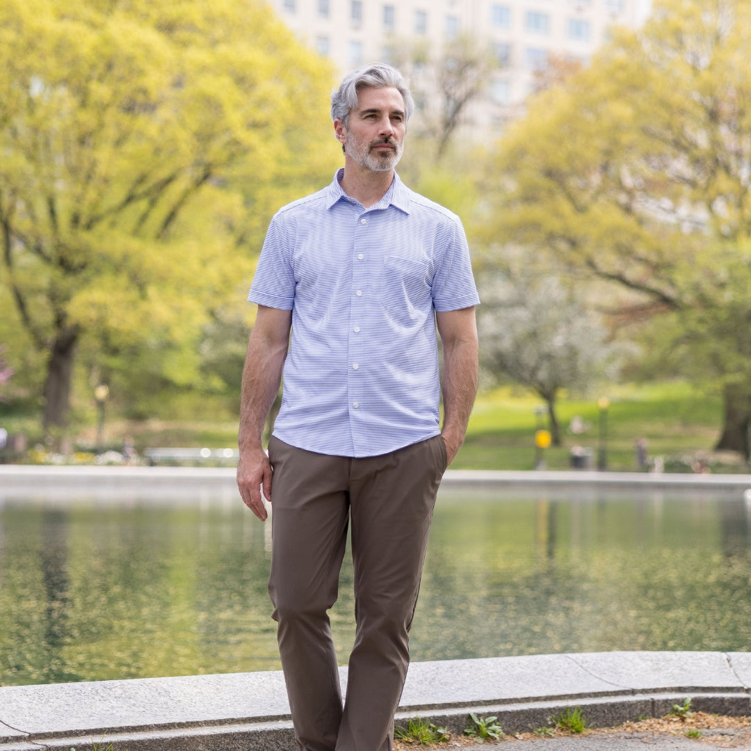 Adaptive Cooling Magnetic Front Short Sleeve Shirt in Blue Stripe worn by a man by the water in a park.