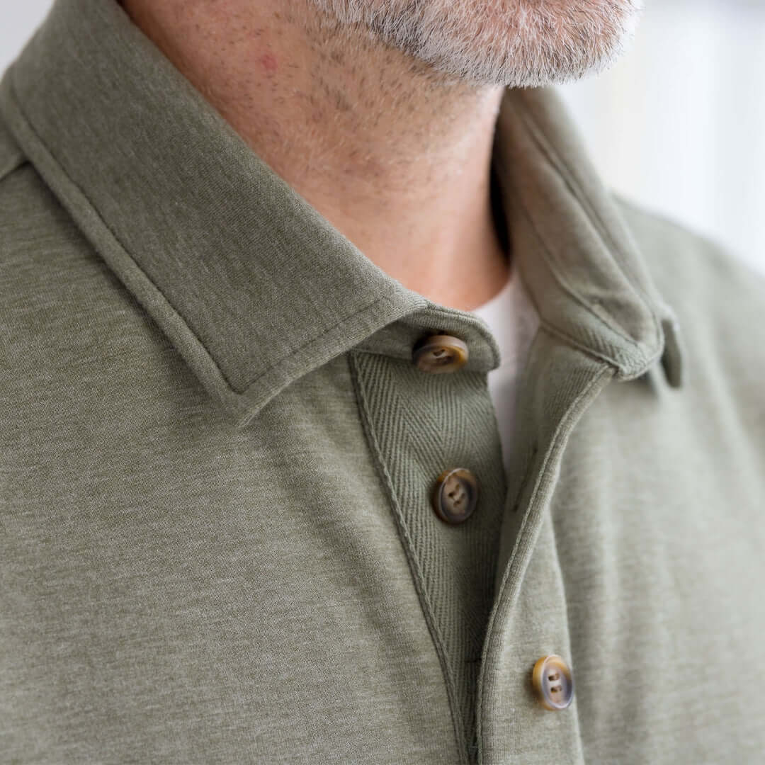 Close-up of a person wearing a green jacket with faux button details Magnetized adaptive sweatshirt.