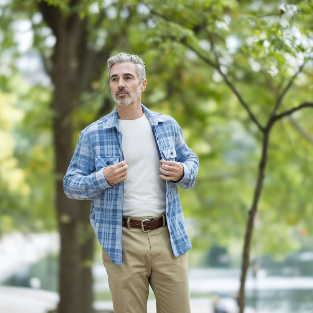 Man wearing adaptive pale blue plaid flannel shirt outdoors, showcasing style and comfort in a natural setting.