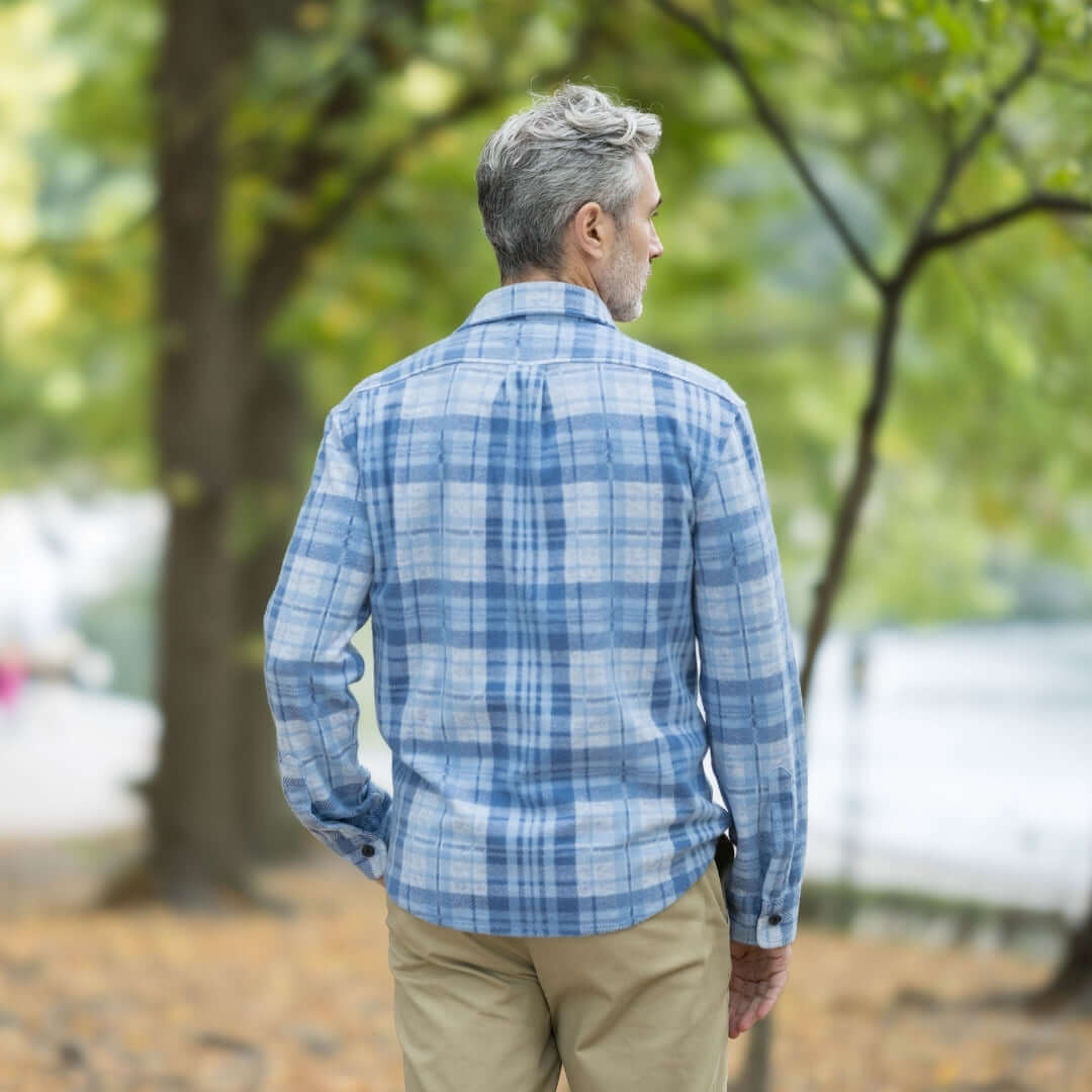Man wearing adaptive pale blue plaid flannel shirt outdoors, showcasing stylish and versatile layering option.
