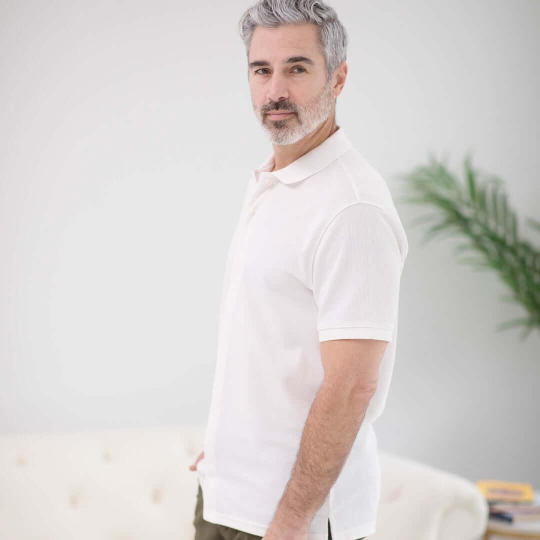 Man wearing a white pique knit short sleeve polo with magnetic closures, showcasing comfort and adaptive design.