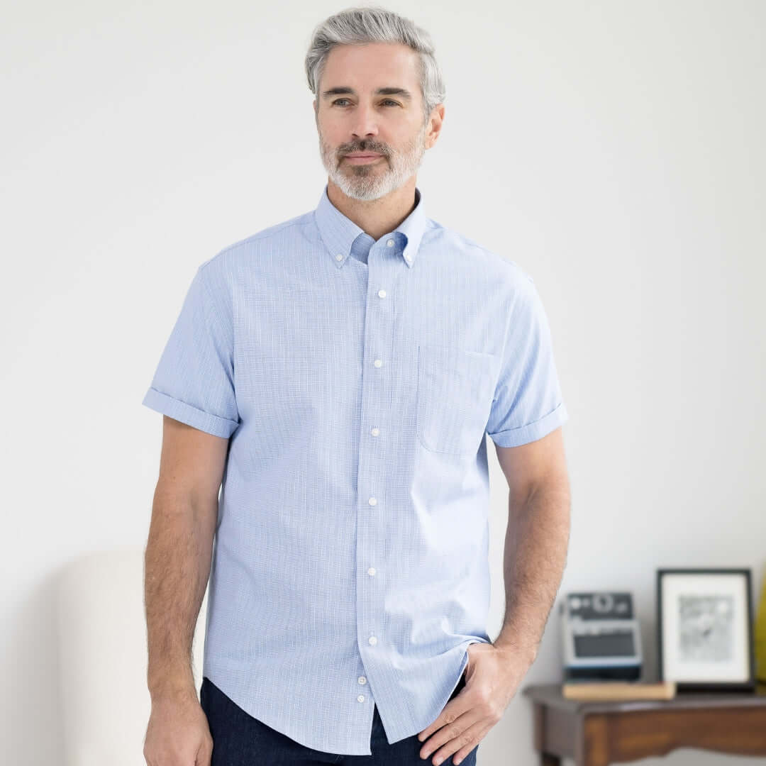 Man wearing a blue check short sleeve button-down collar shirt with magnetic closures, ideal for those with limited mobility.