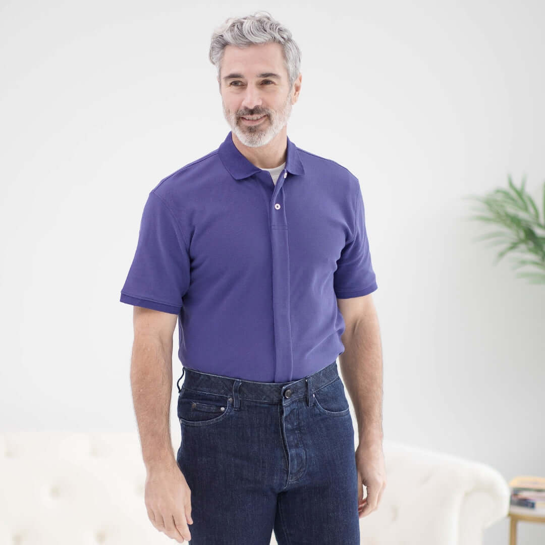 Man wearing a blue pique knit polo shirt with short sleeves and magnetic closures, designed for easy dressing.