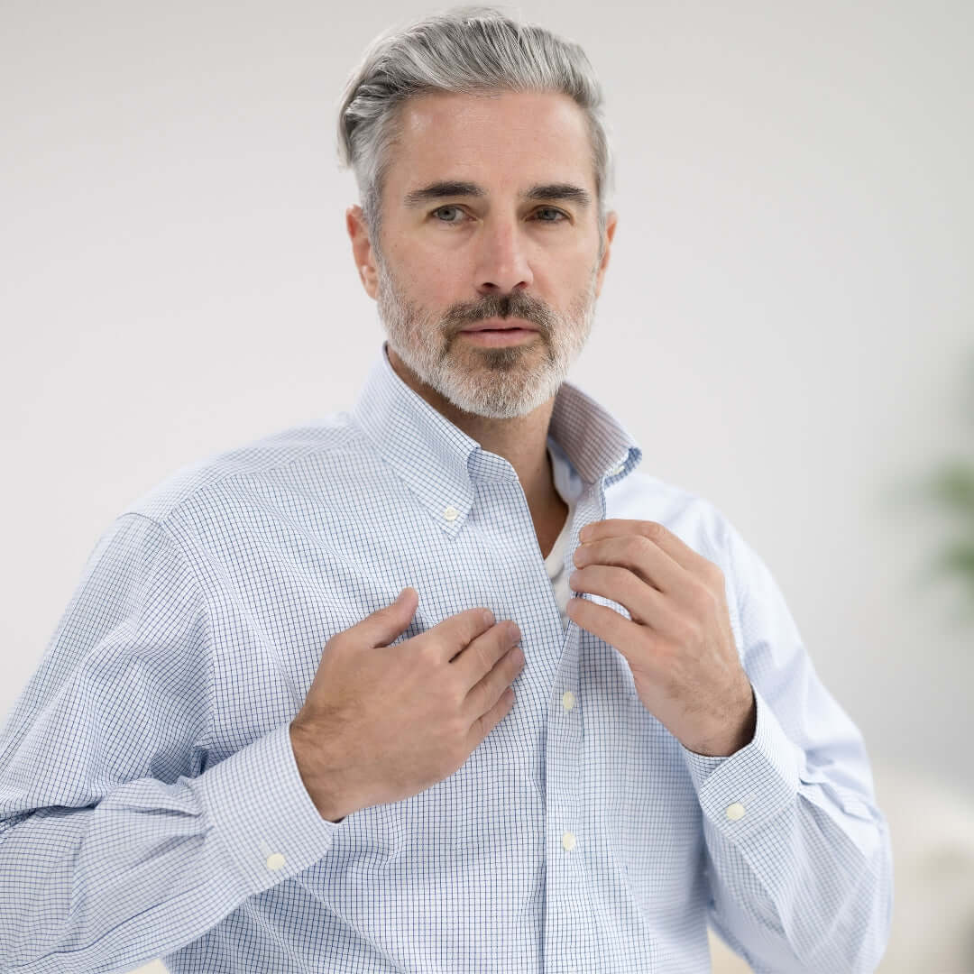 Man adjusting collar of Brooks Brothers MagnaReady blue and white check shirt with magnetic closures.