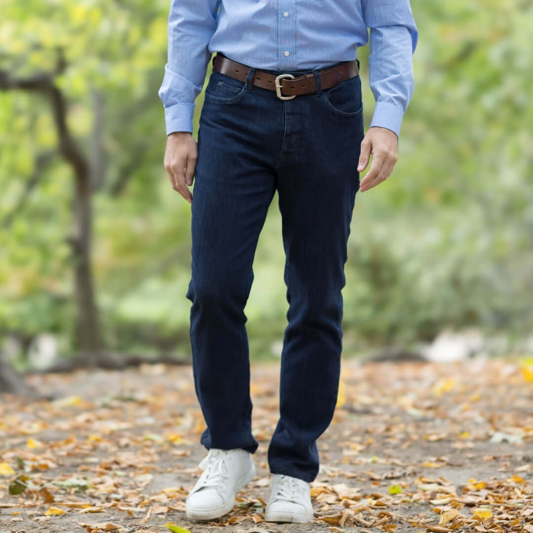 Man wearing Indigo 'MVP' Five Pocket Jean with Magnetic Closures, styled with a blue shirt in a fall setting.