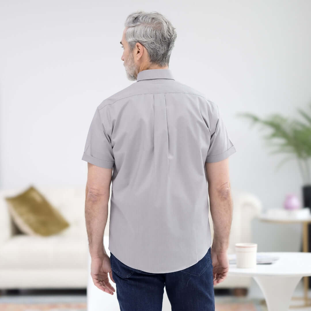 Back view of a man wearing a Dove Grey short sleeve button-down shirt in a modern living room.