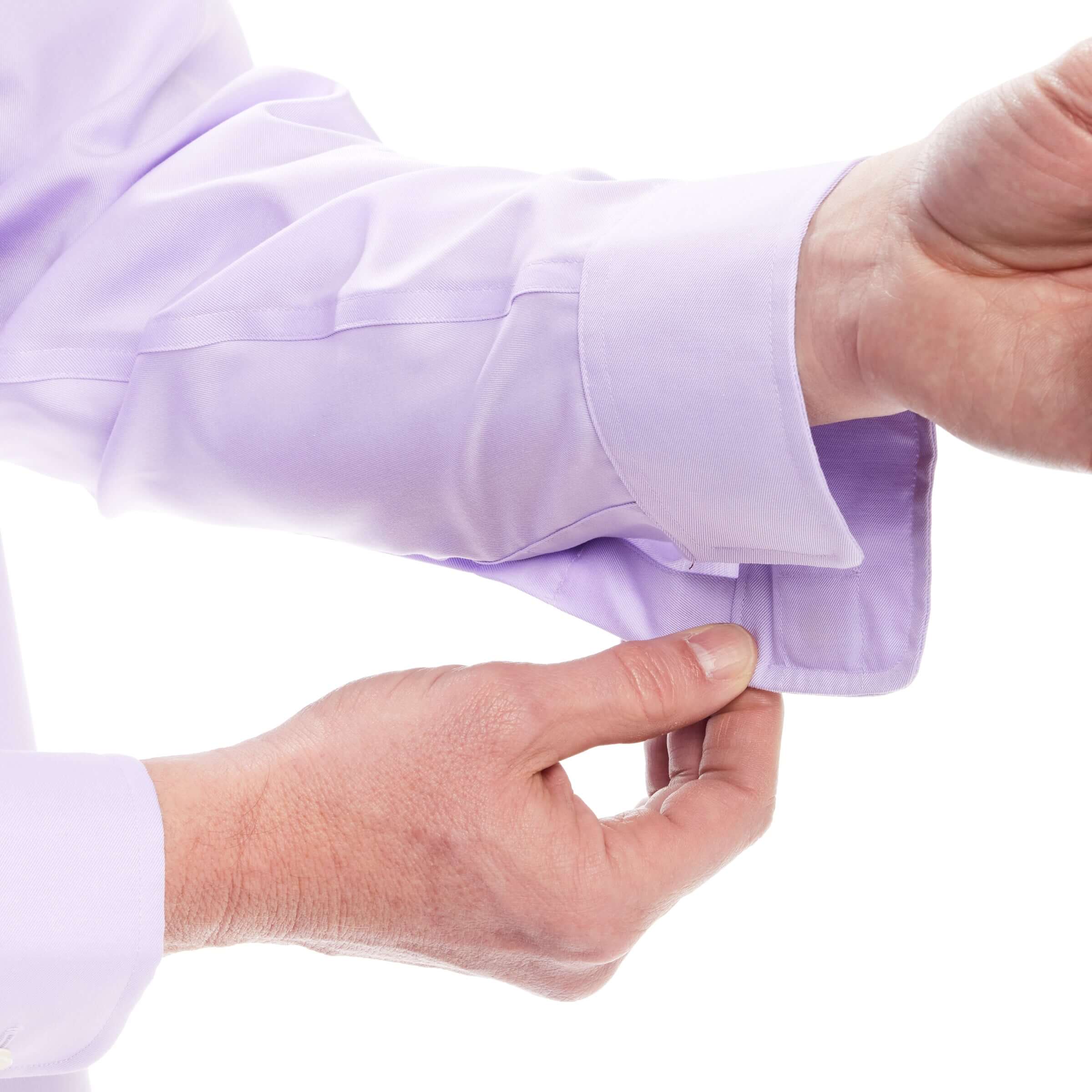 Close-up of a hand adjusting the sleeve of a lavender shirt with magnetic closures, showcasing style and comfort.