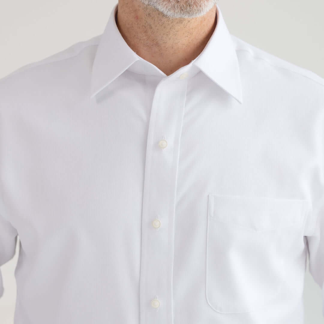 Close-up of a man wearing the Long Sleeve White 'Ryan' Dress Shirt with traditional buttons and a spread collar.