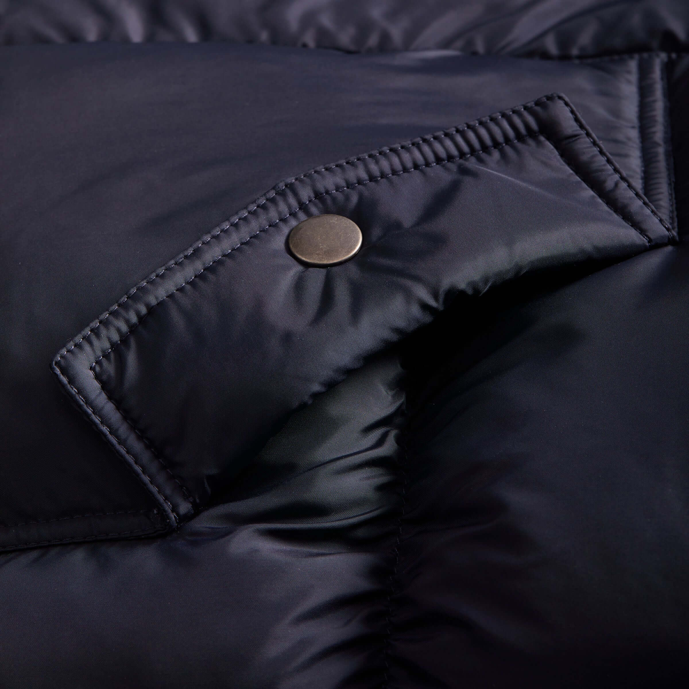 Close-up of the navy MagnaMini kids puffer coat showing the magnetic closure and water-resistant material.