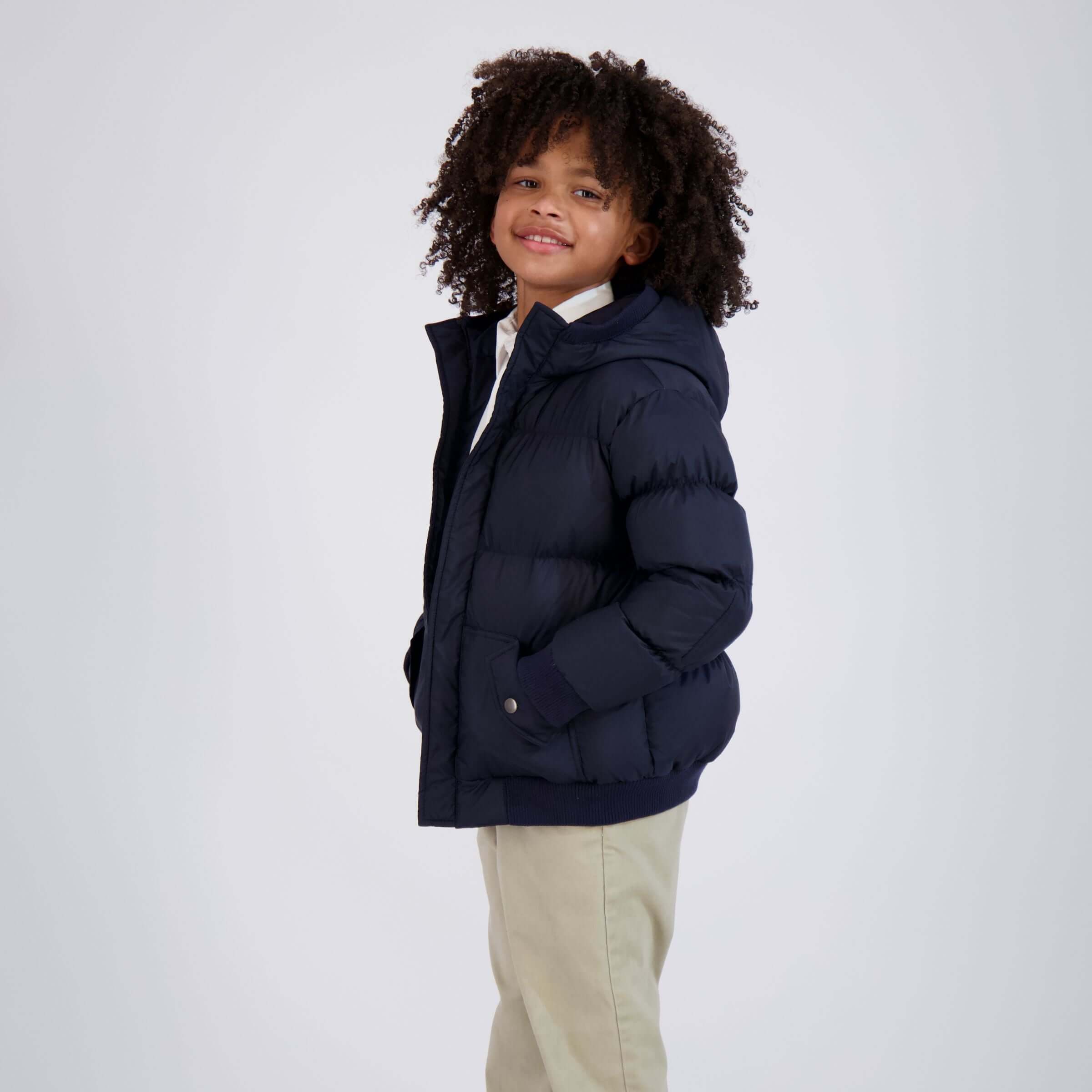 Child wearing a Navy MagnaMini Kids Magnetic Puffer Coat with Hood, smiling and ready for adventure.