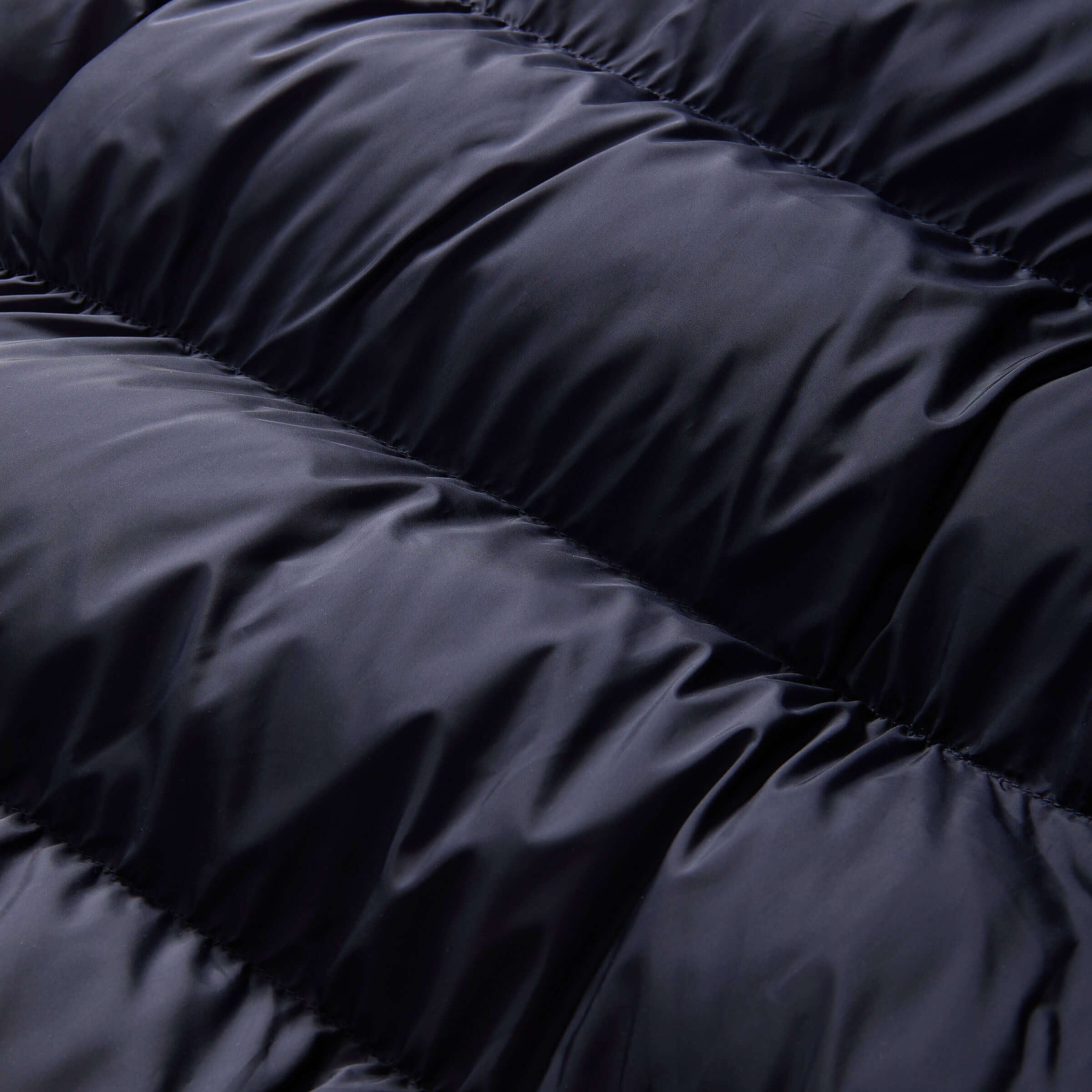 Close-up of navy puffer coat fabric showcasing its water-resistant texture and cozy, quilted design.
