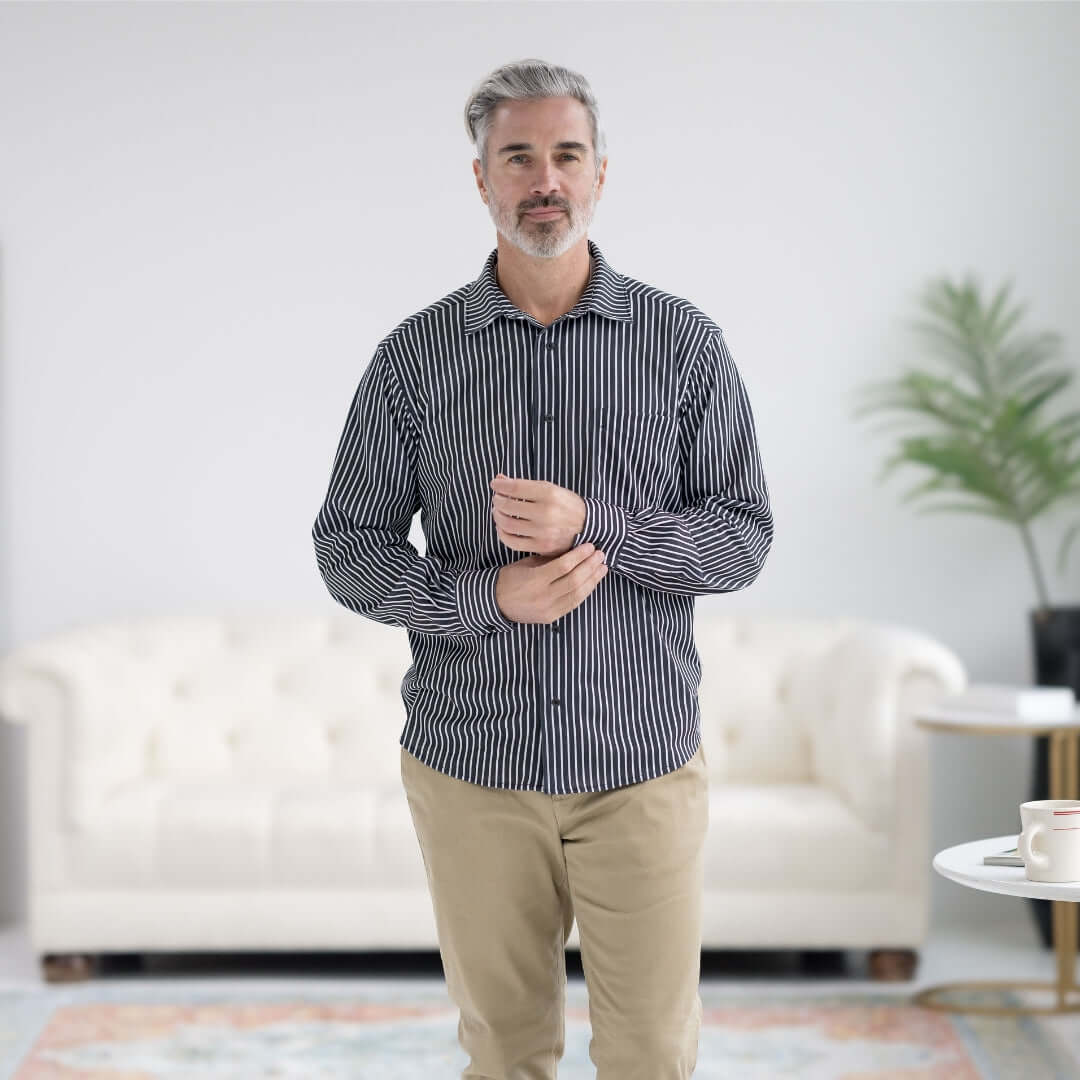 Man wearing MagnaReady black stripe magnetic long sleeve tech shirt in a stylish living room setting.